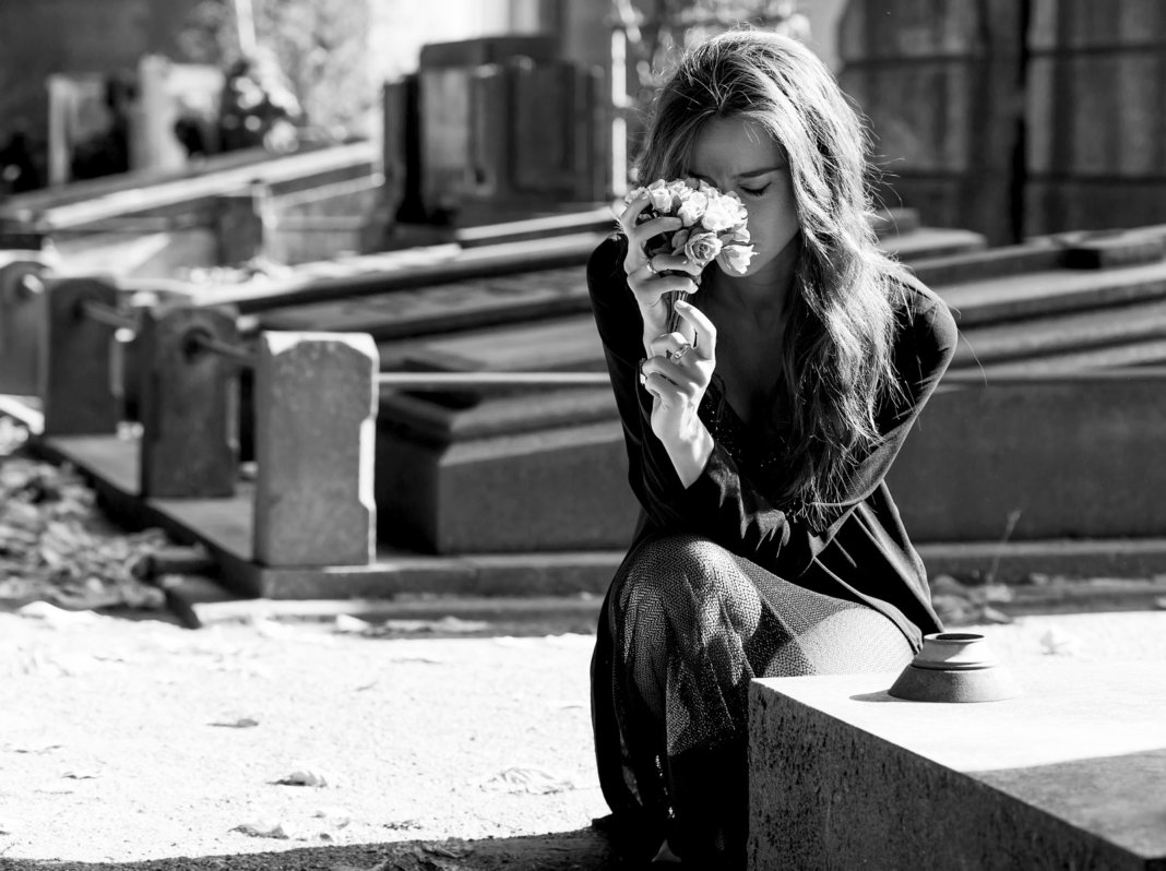 Sad woman holding bunch of flowers near a grave monochrome QUANDO PERDER UM ENTE QUERIDO, LEMBRE-SE DESSAS 5 COISAS